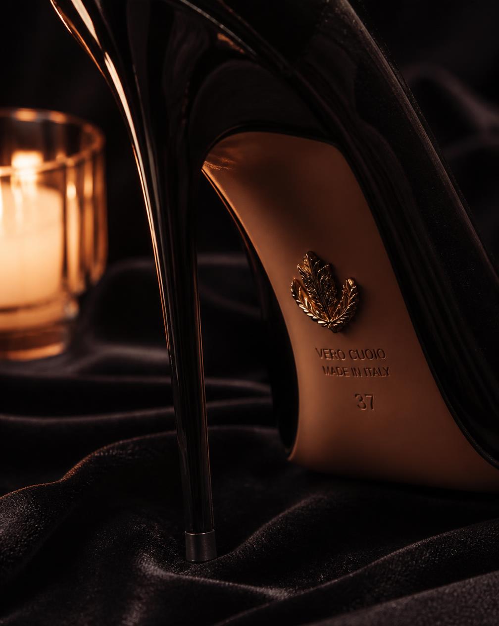 Close detail of a stiletto heel tip and leather sole on black velvet by candlelight